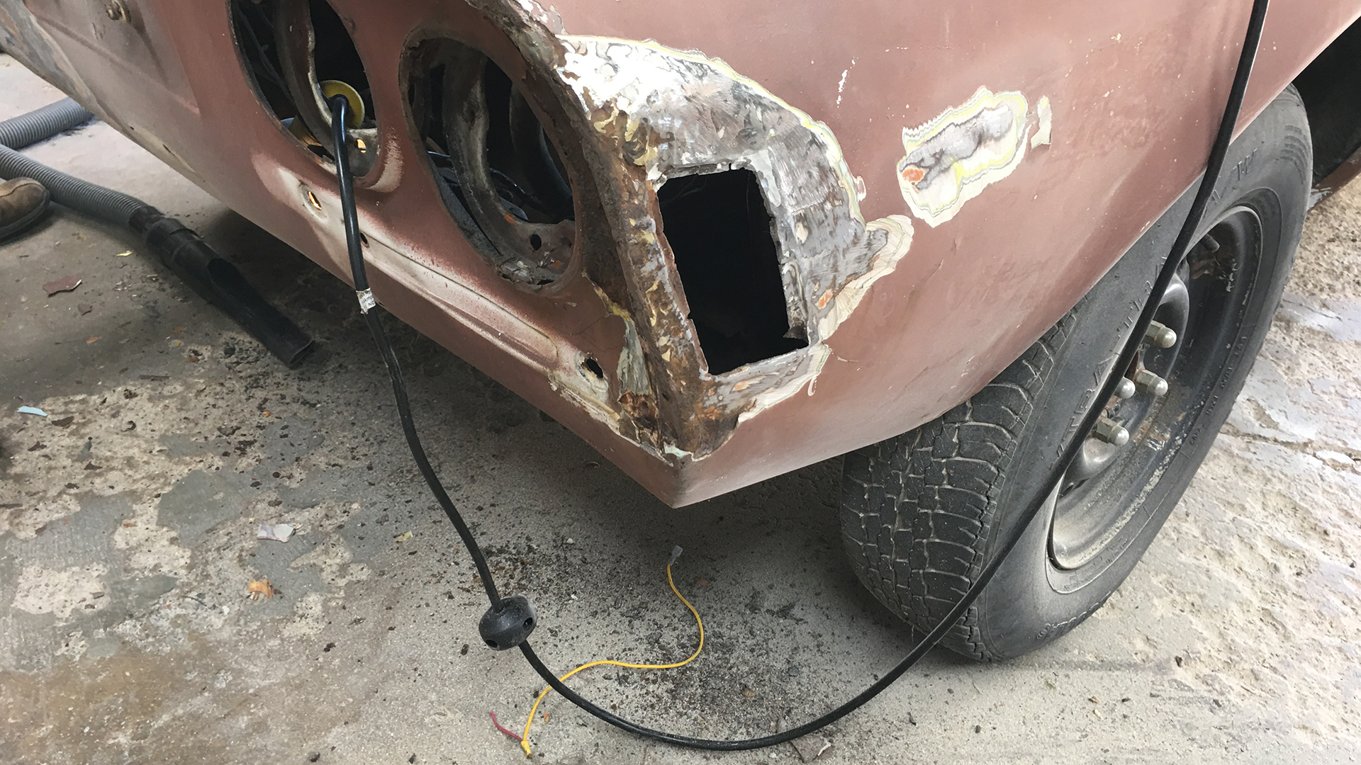 The rear passenger quarter of a rusty Opel GT.