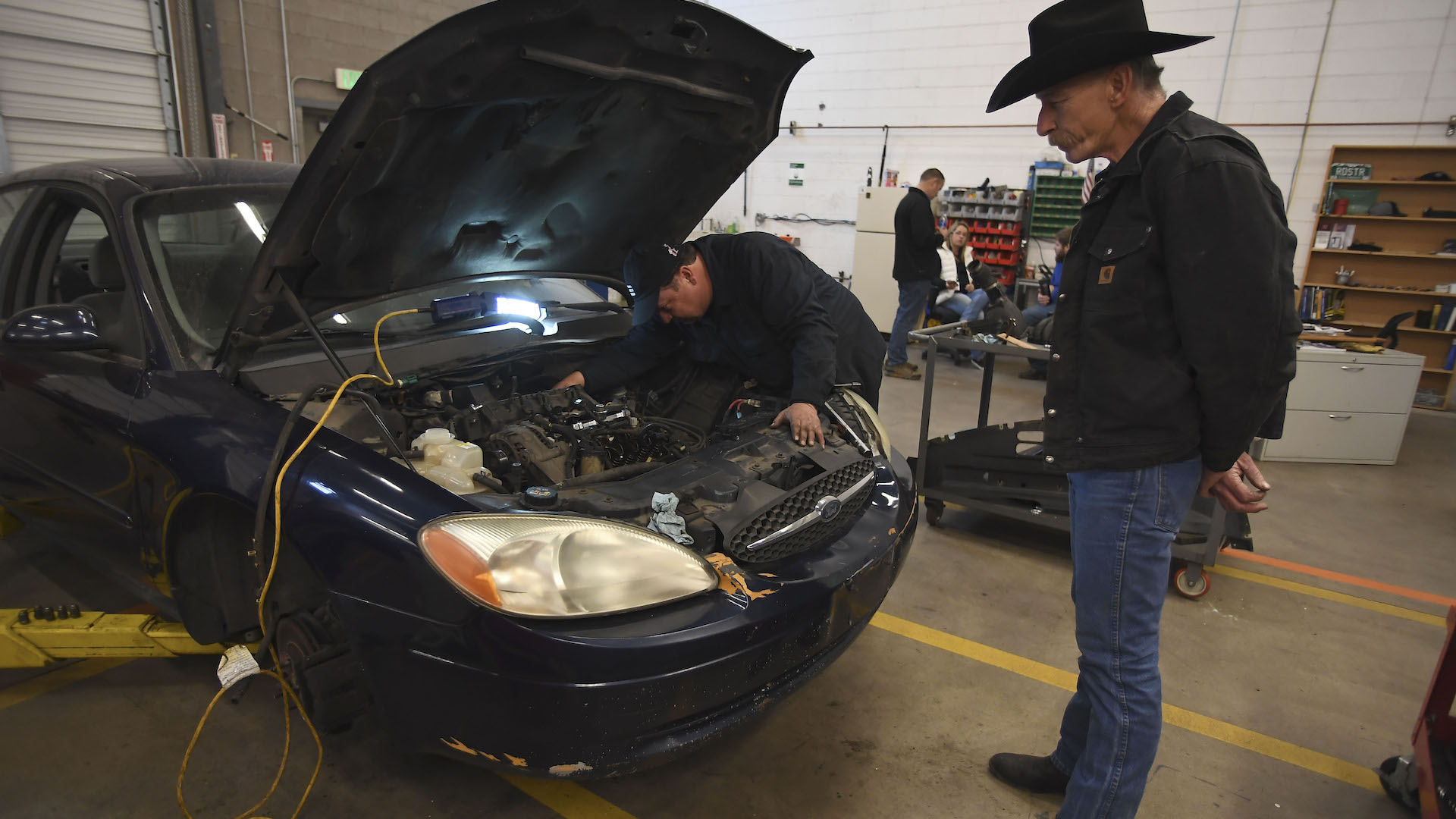 DENVER, CO - NOVEMBER 6: Senior fleet mechanic Res bacon stands back as he watches Mike Stueve, who graduated from the rehab program and is now an employee, work on a car in the auto-repair shop on November 6, 2017. The Denver Rescue Mission's New Life Rehab Program helps men and women who are homeless and struggling with sobriety to stay sober, hone their job readiness skills and get back to being a "self-sufficient, contributing citizen". One of the last phases of the program is getting the clients into work therapy. One work therapy option is working for the mission's auto-repair shop. (Photo by John Leyba/The Denver Post via Getty Images)