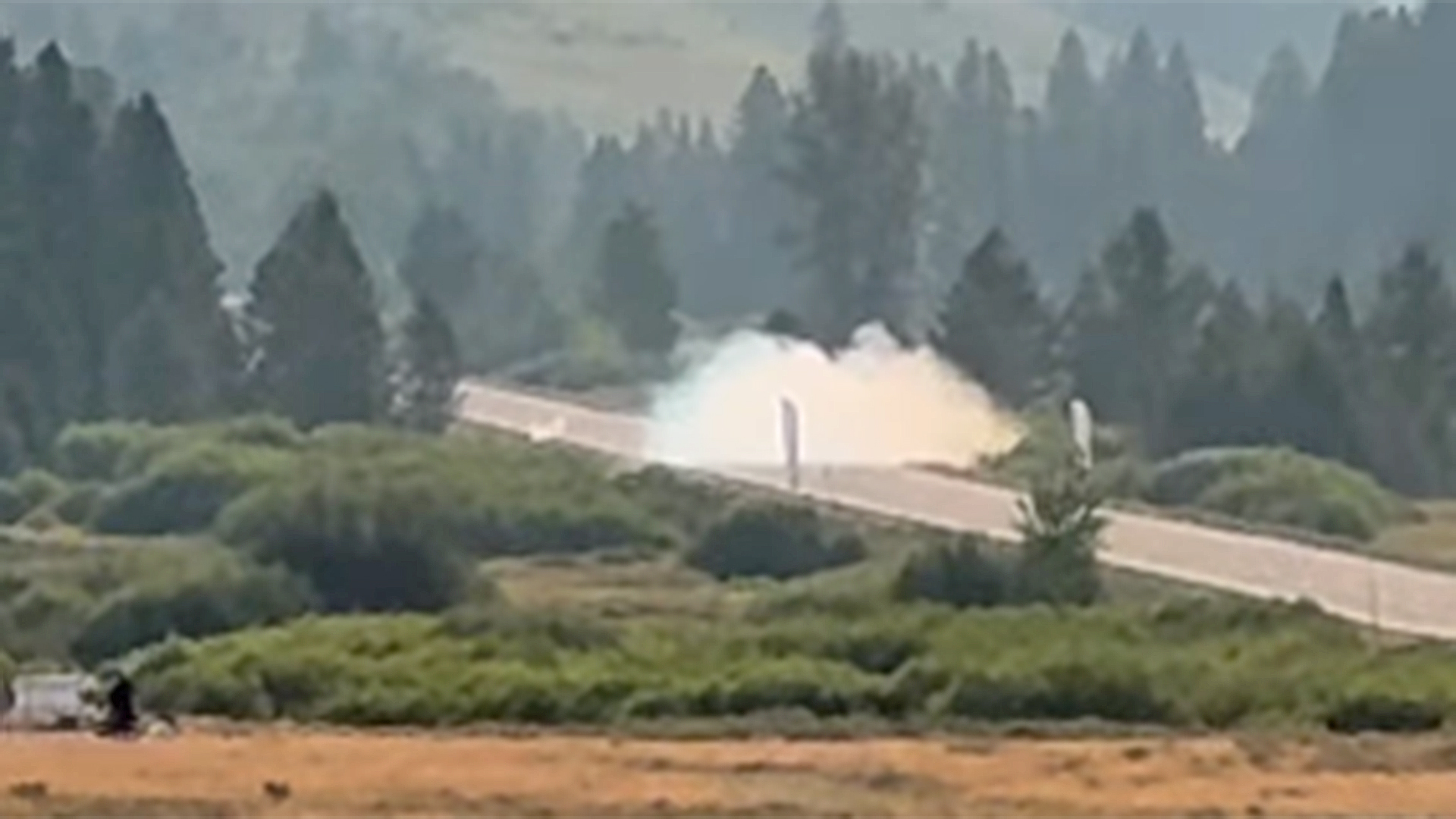 Screenshot of a large plume of smoke in the distance left by a crashing Porsche 911 at the Sun Valley Tour De Force.