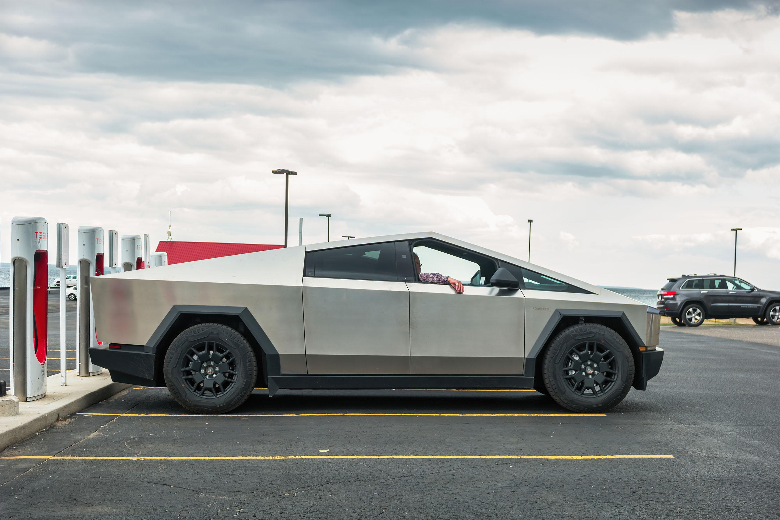 A Tesla Cybertruck electric pickup truck is being charged in Mackinaw City, Michigan, USA on an overcast day.