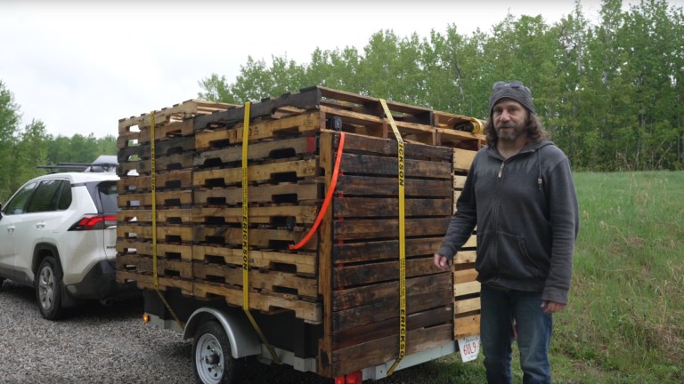 A stealth camper trailer disguised as a stack of wooden pallets.