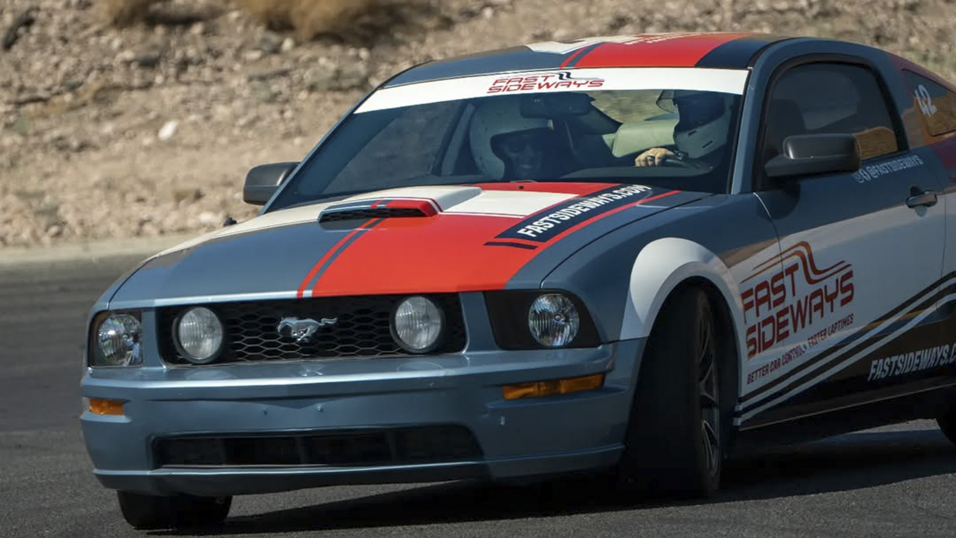 Two guys in a Ford Mustang race car at a driving school.