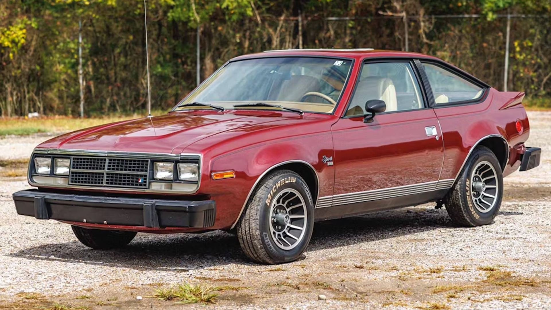AMC Spirit, red two-door car, pointed left.