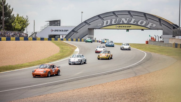 Porsche 911s driving under the Dunlop Bridge at the Le Mans Classic