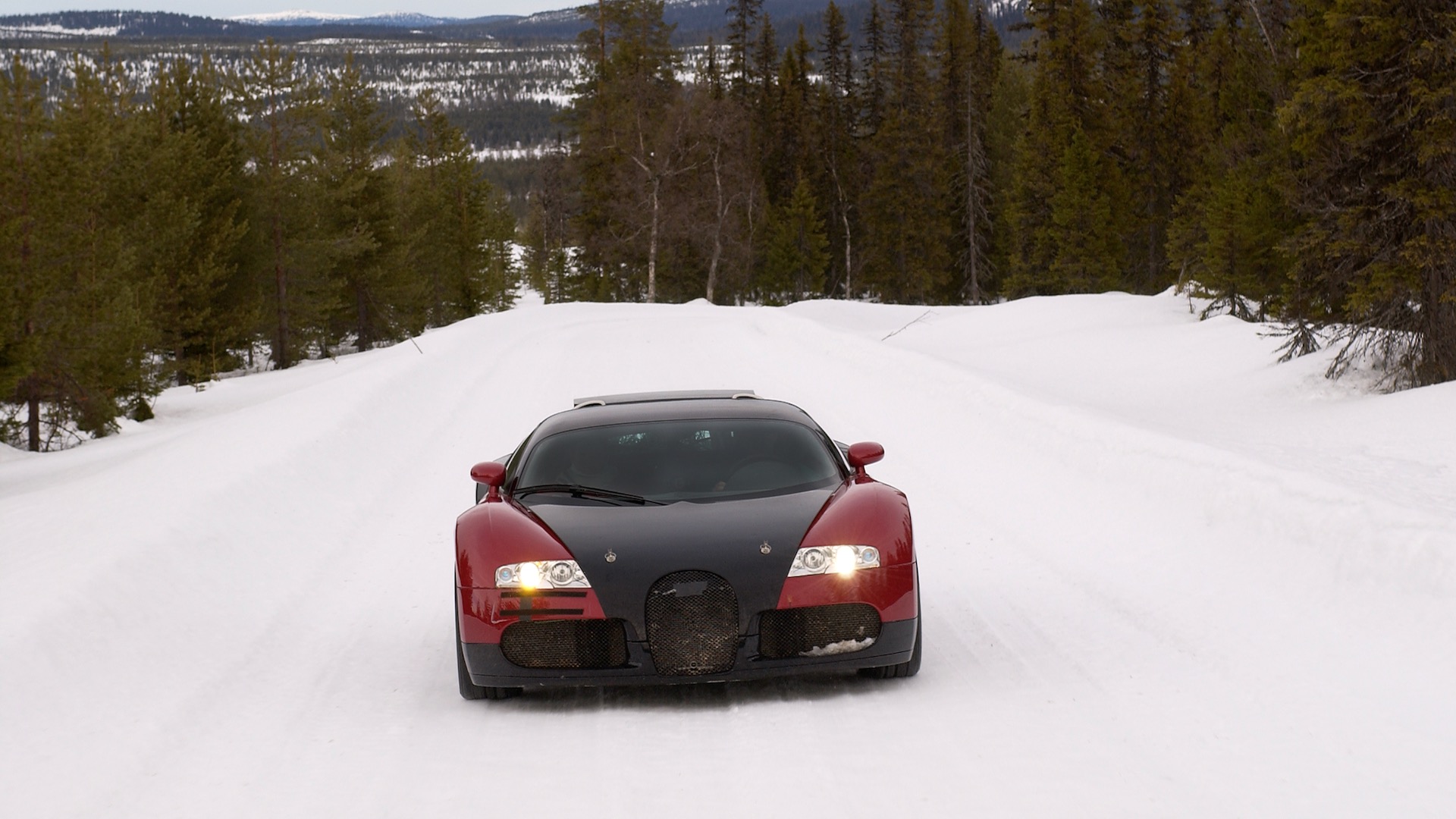 Front view of a Bugatti Veyron prototype driving up a snow-covered hill.