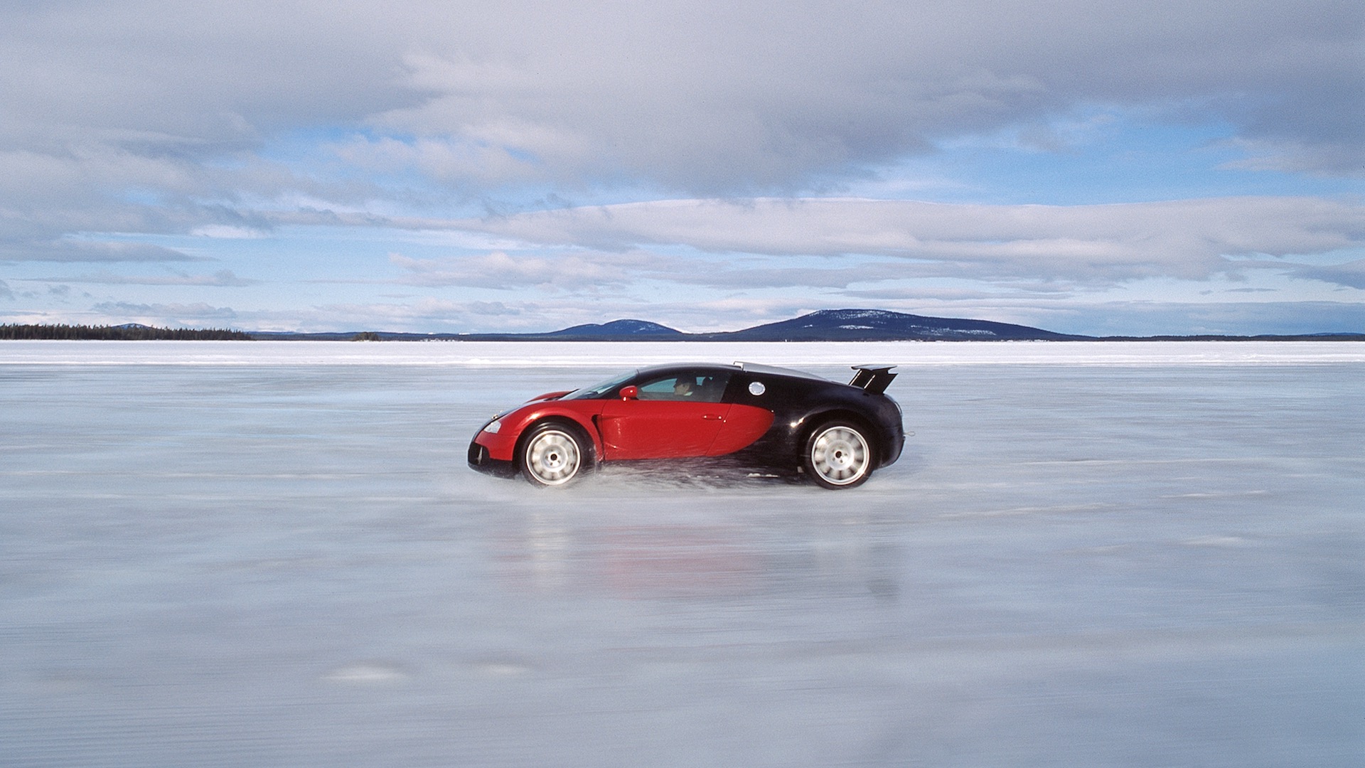 A red and black Bugatti Veyron prototype driving on ice.