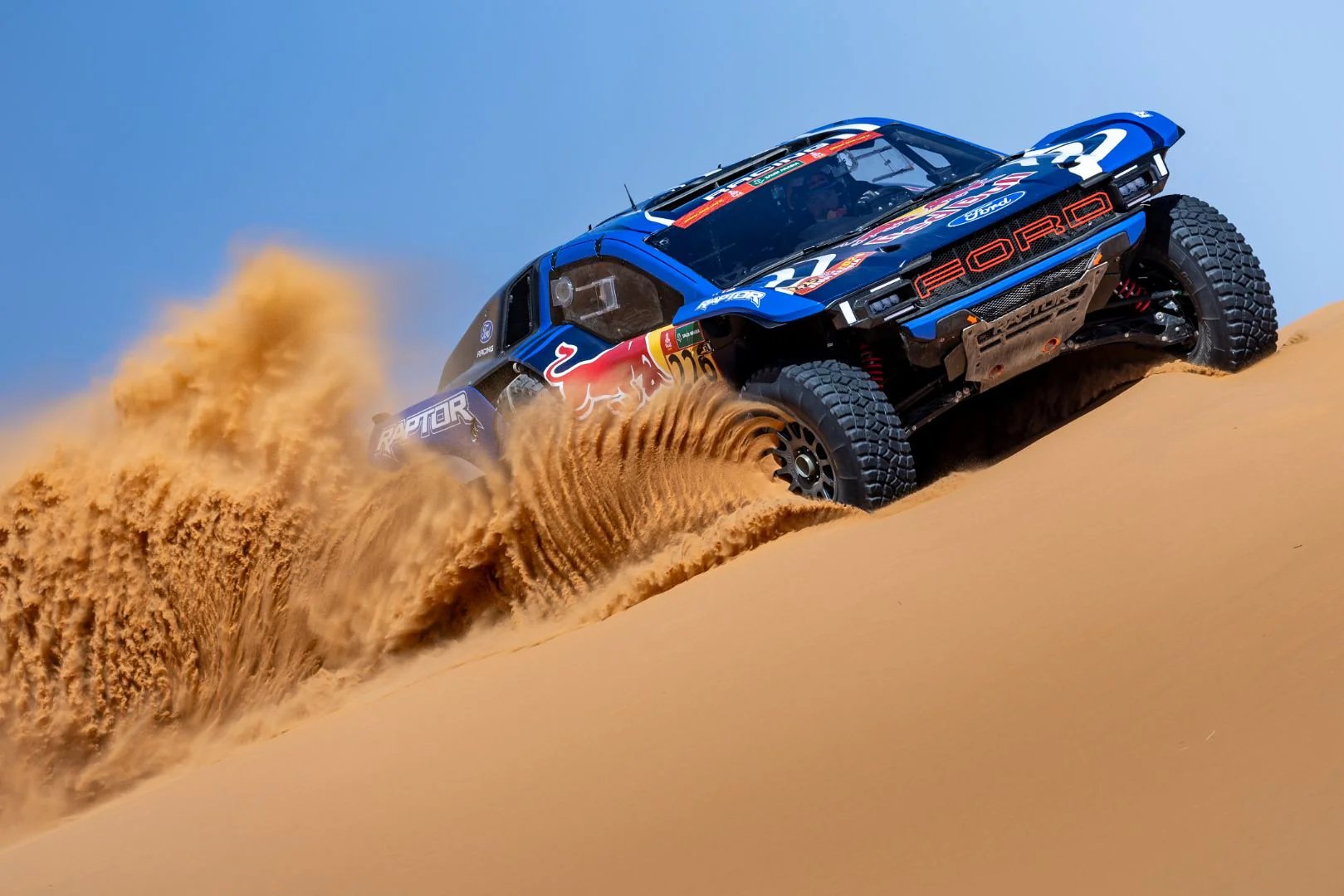 Ford Raptor T1+ race car blasting through sand.