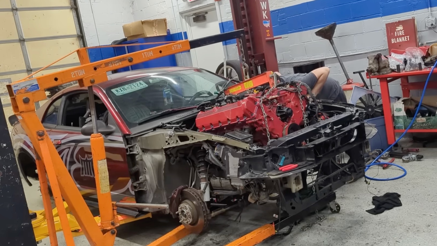 Triton V10 on a hoist being lowered into a Ford Mustang engine bay.