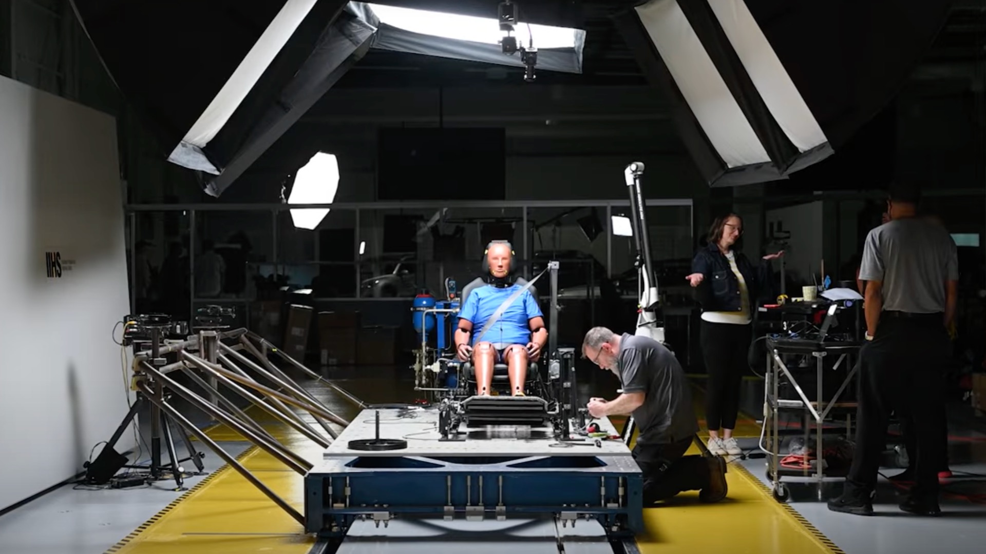 Crash test dummy seated in sled for IIHS whiplash prevention test.