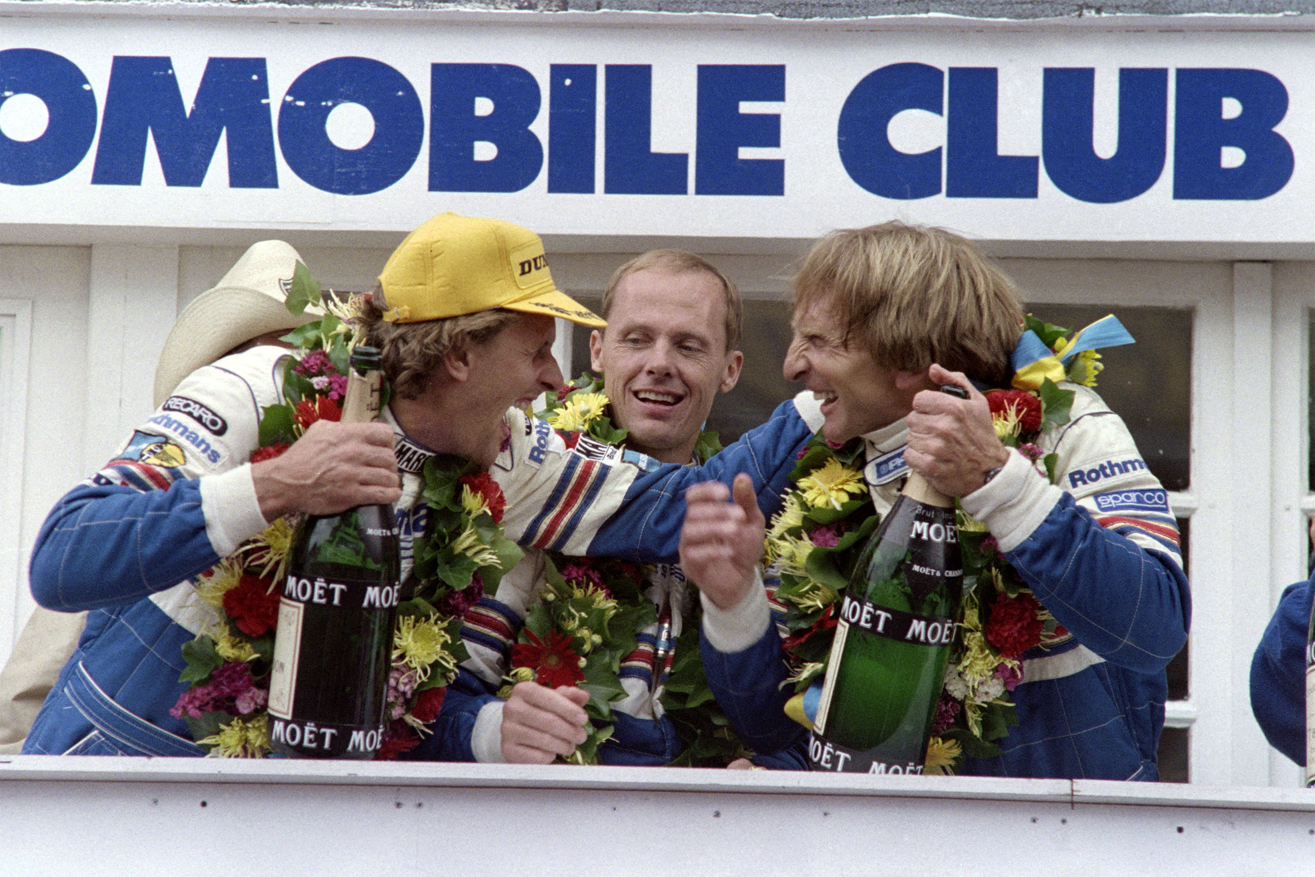 From left, Hans-Joachim Stuck, Al Holbert, and Derek Bell celebrate on the podium after winning the 1987 24 Hours of Le Mans, the second consecutive Le Mans victory for this driver team and the Porsche 962.