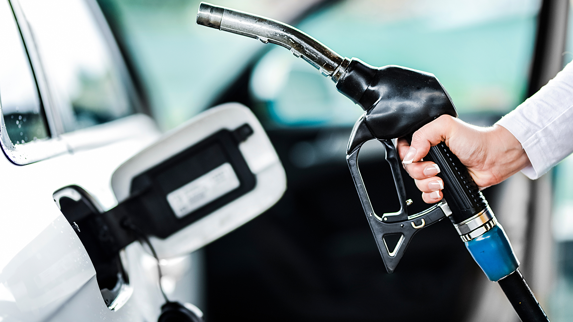 Woman pumping petrol at gas station into vehicle. Hand holding a pistol or nozzle pump prepare to refuel car with gasoline.