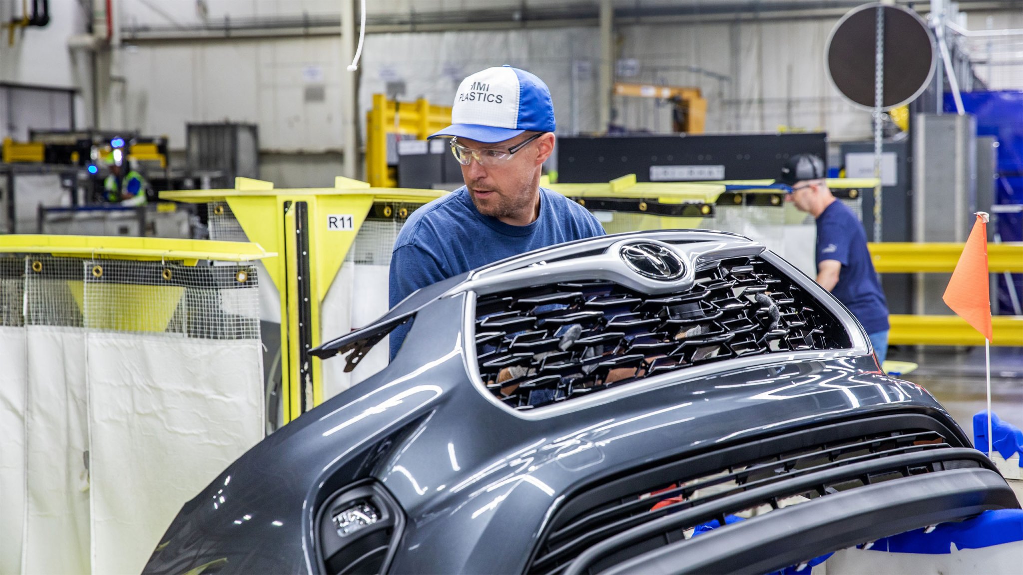 A Toyota employee holds the front clip of a Toyota Highlander at the company's Indiana manufacturing plant.