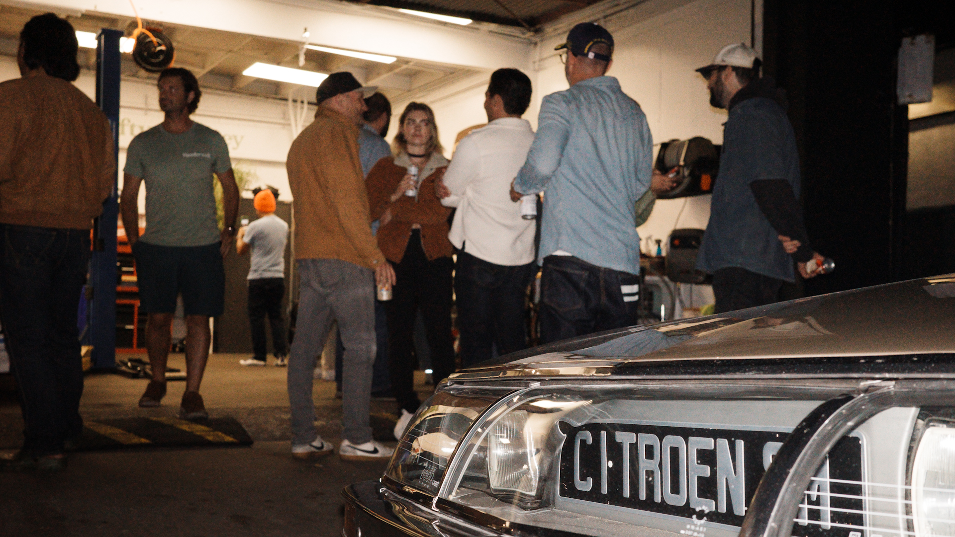 Crowd hanging out at auto shop.