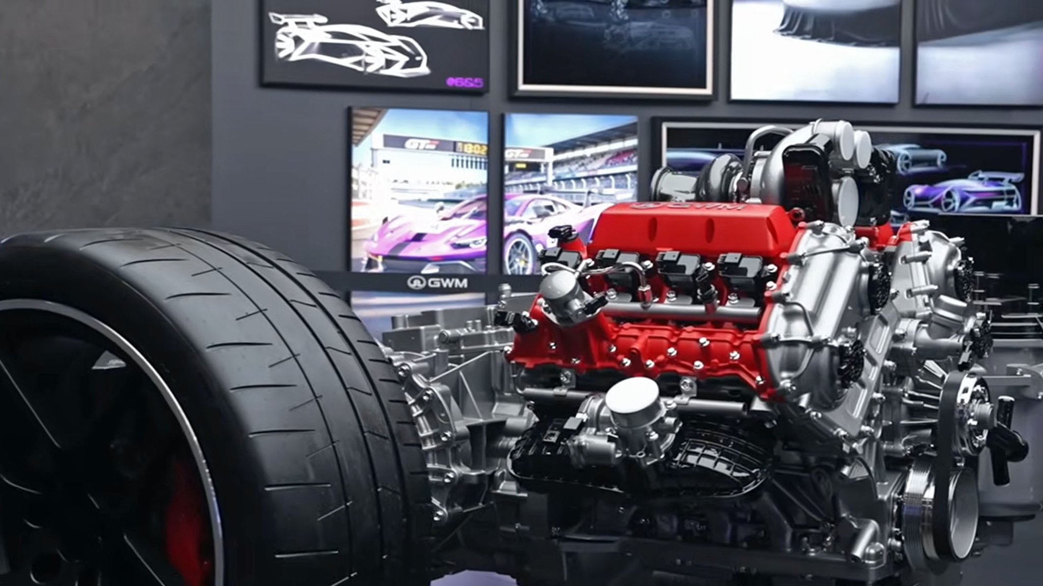 A close-up of GWM's "GF" V8 powertrain on display at Auto China 2026, with renderings of a GT3 car in the background.