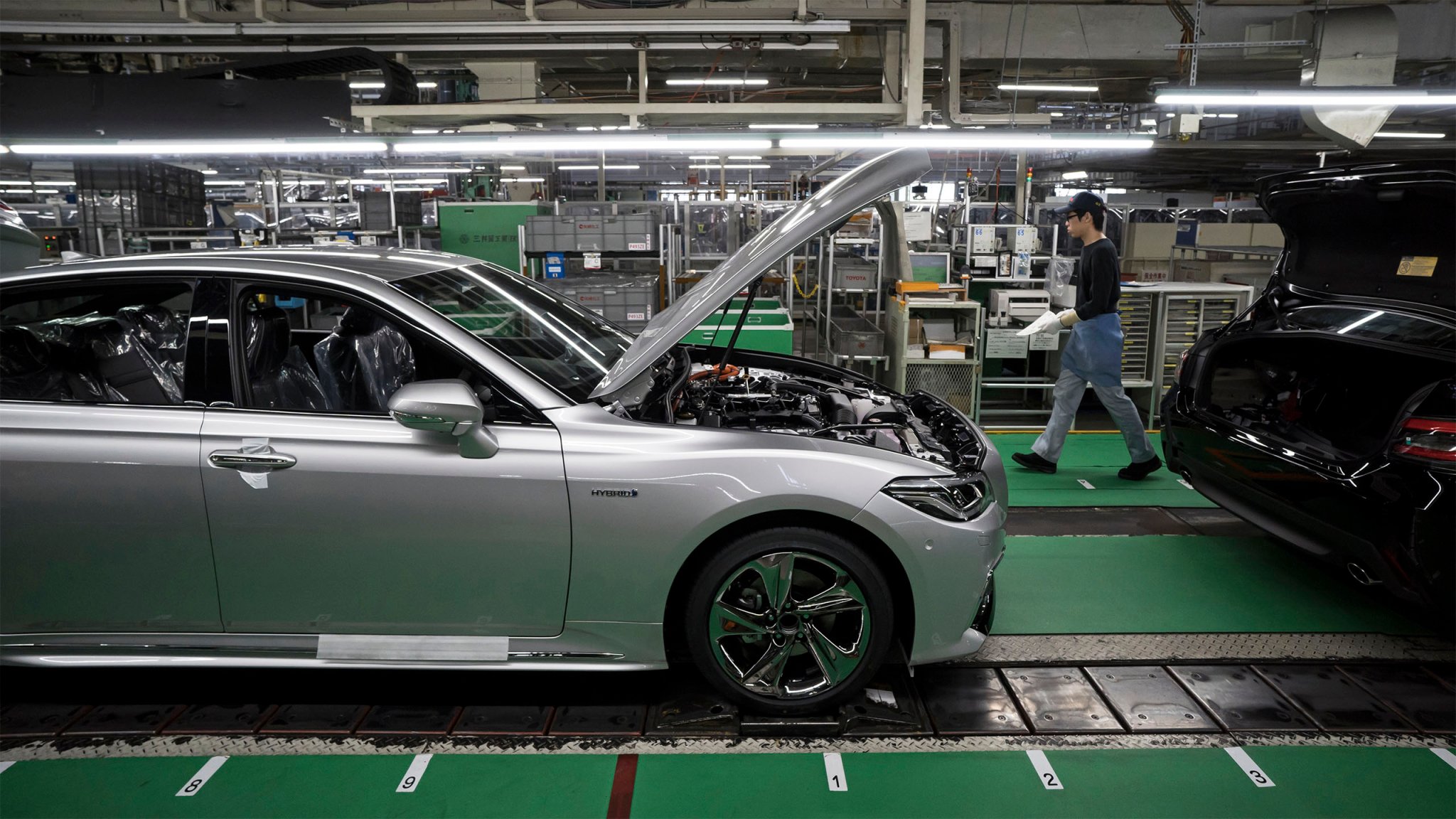 A worker walks near a Toyota Motor Corp Crown vehicle manufactured on the production line of the company's Motomachi factory.