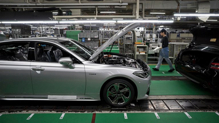 A worker walks near a Toyota Motor Corp Crown vehicle manufactured on the production line of the company's Motomachi factory.