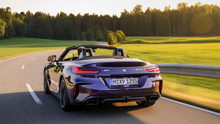 Purple BMW Z4 driving at sunset, rear 3/4 view