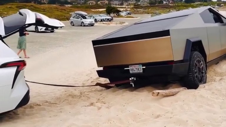 A Toyota Sienna helping a stuck Tesla Cybertruck on a beach