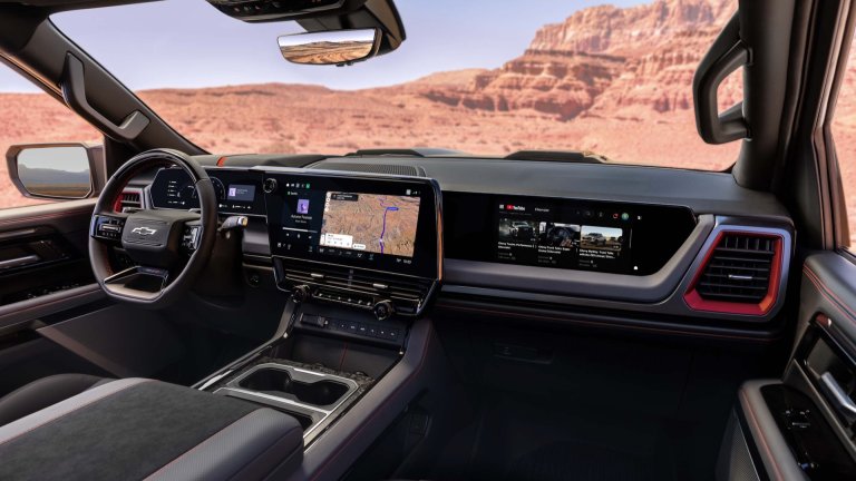 2027 Chevrolet Silverado 1500 ZR2 with Dark Galvinized interior. Interior image from front passenger viewpoint. Highlighting expanded tech, carbon fiber accents and Torch Red detailing.