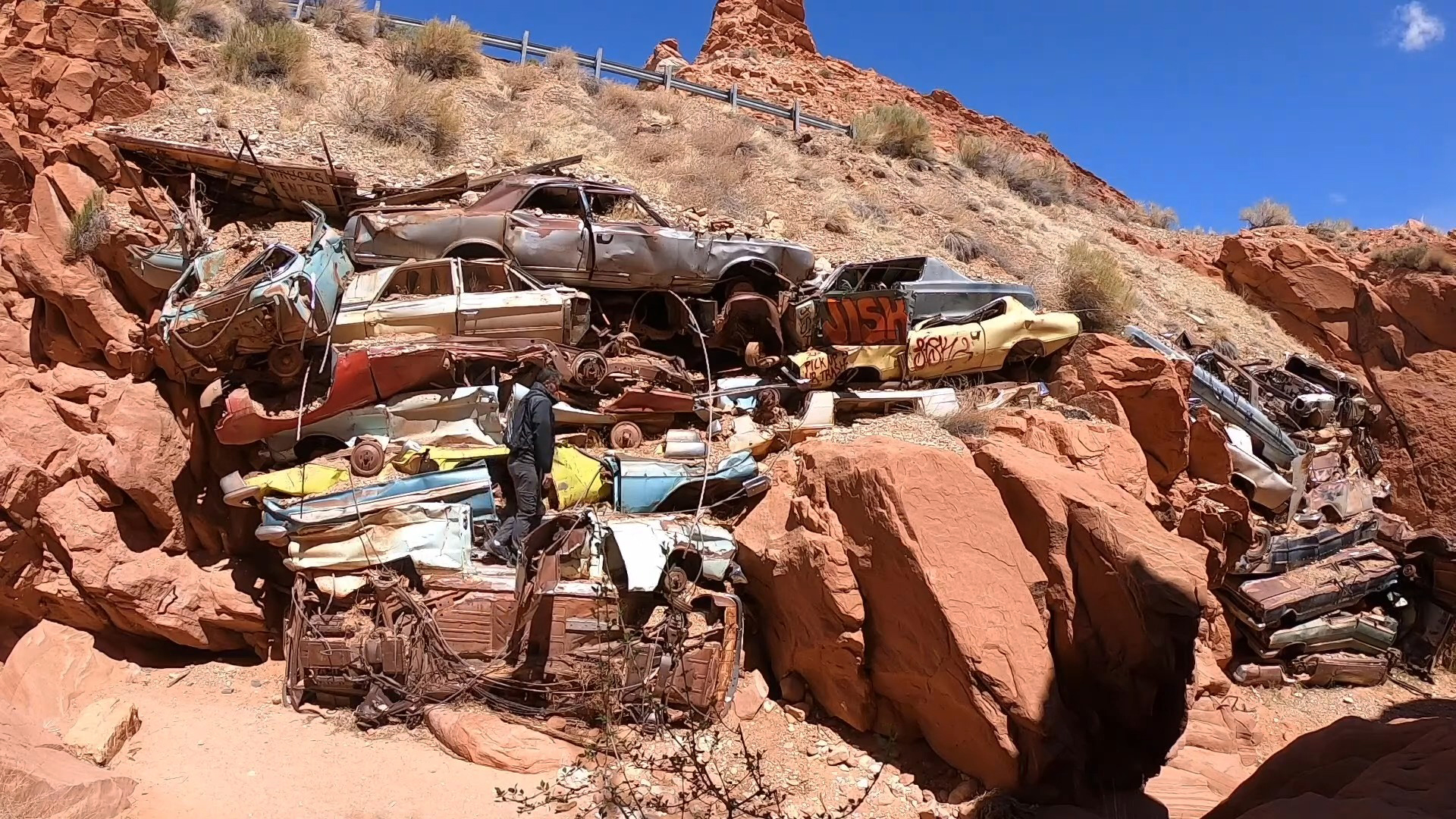 Man climbing Catstair Canyon car pile off Highway 89