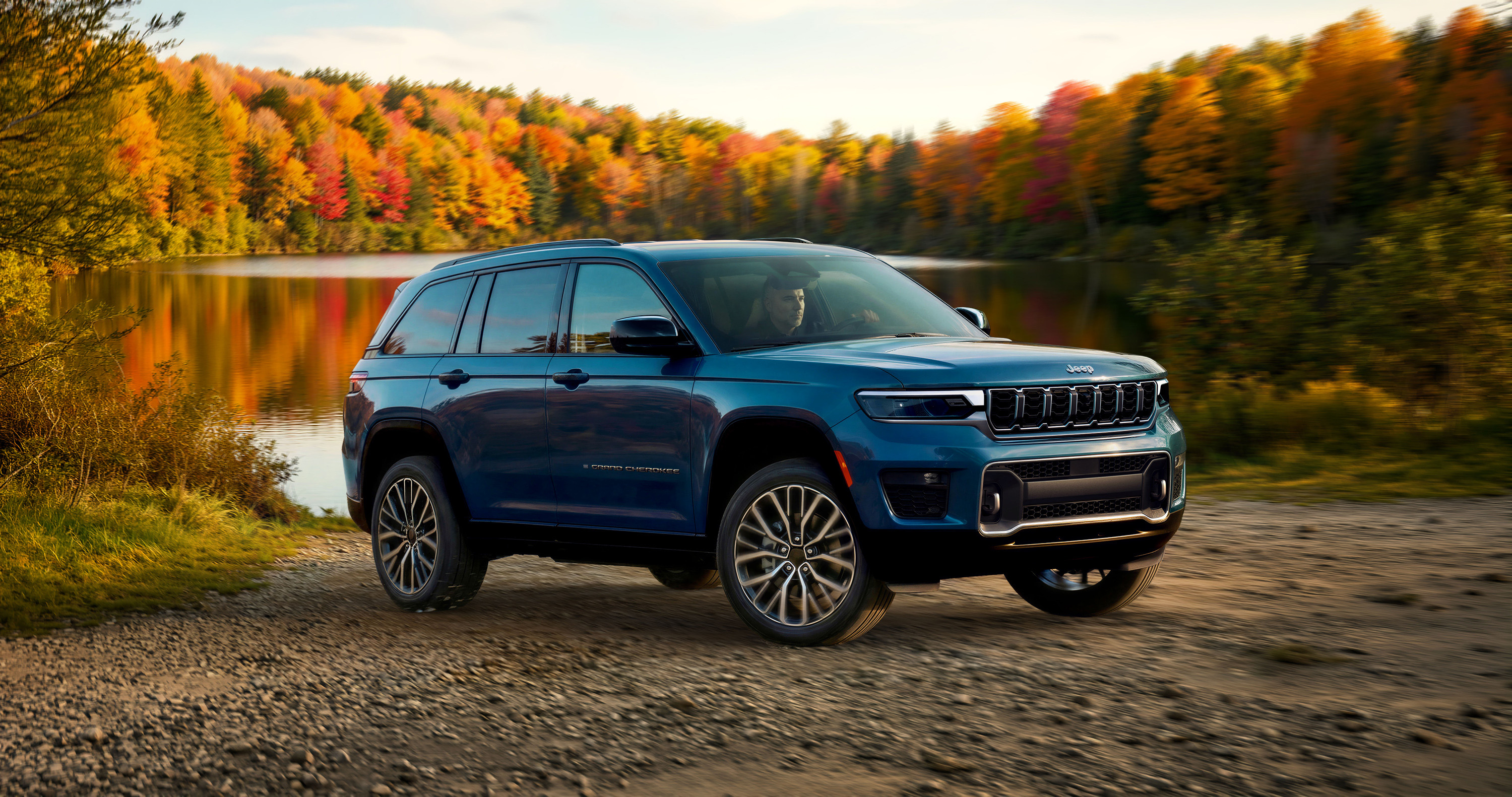 The 2027 Jeep® Grand Cherokee Overland front three-quarter view exiting a dirt trail.