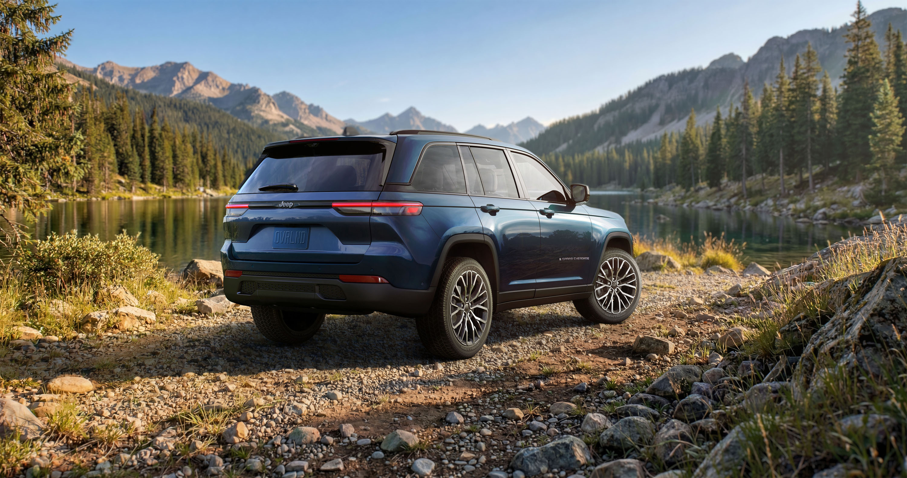 The 2027 Jeep® Grand Cherokee Overland rear three-quarter view parked in front of a body of water.