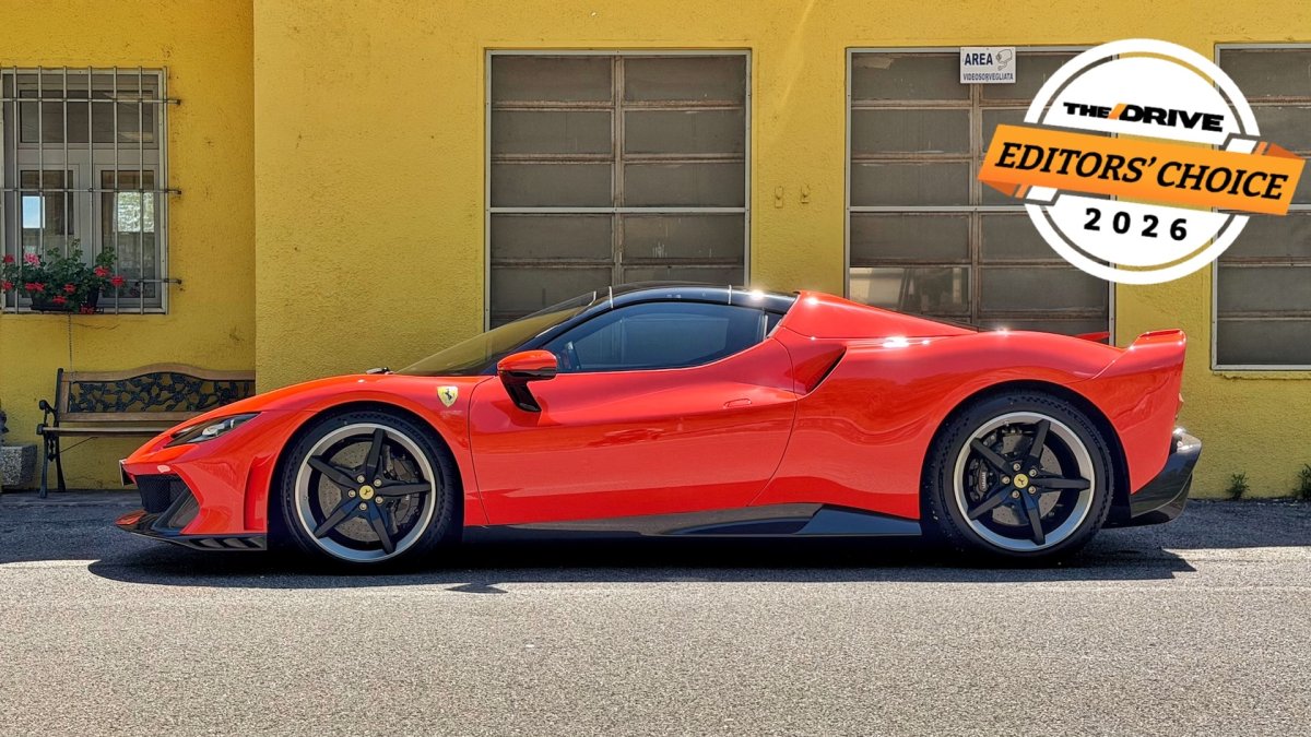 Un'auto sportiva rossa con tettuccio aperto, dettagli in carbonio e aerodinamica avanzata, in un'area di parcheggio