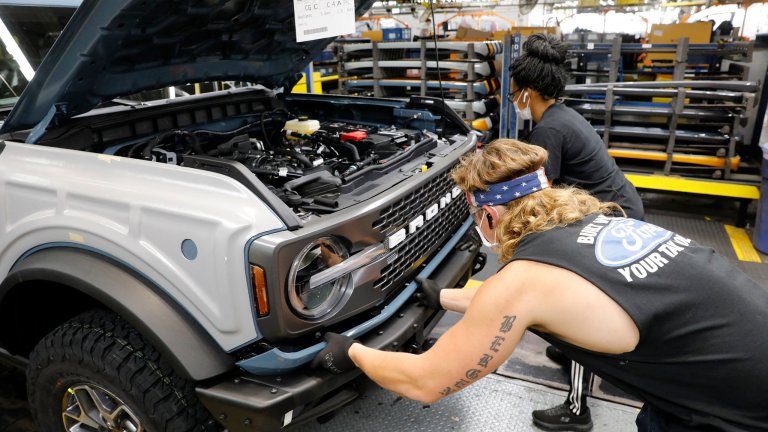 Assembly line workers work on a Ford Bronco SUV in production.