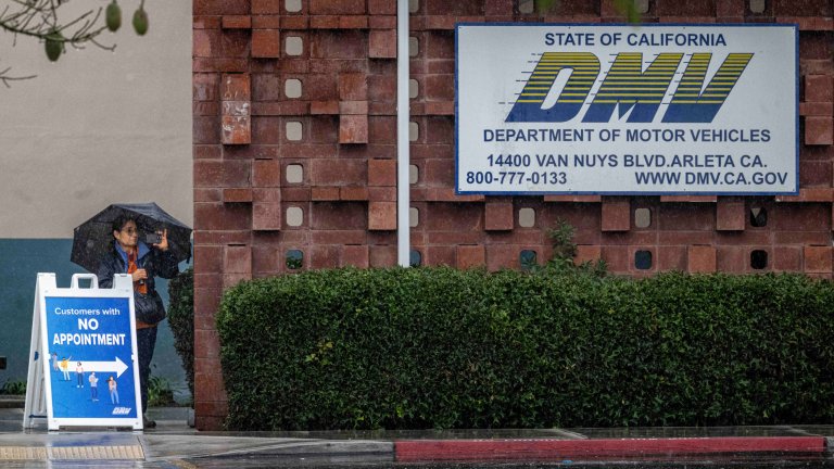 People walk through the rain at the Arleta DMV in Arleta on Thursday, November 20, 2025.