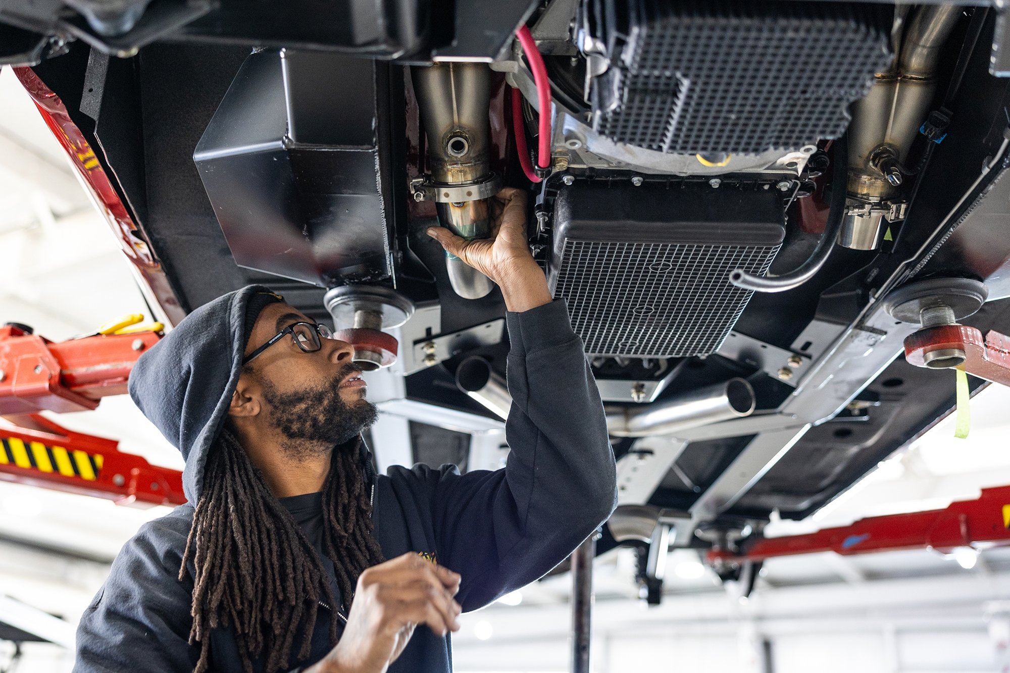 Mechanic fits a custom exhaust.