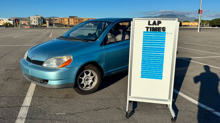 Abdul's Toyota Echo track car next to a leaderboard