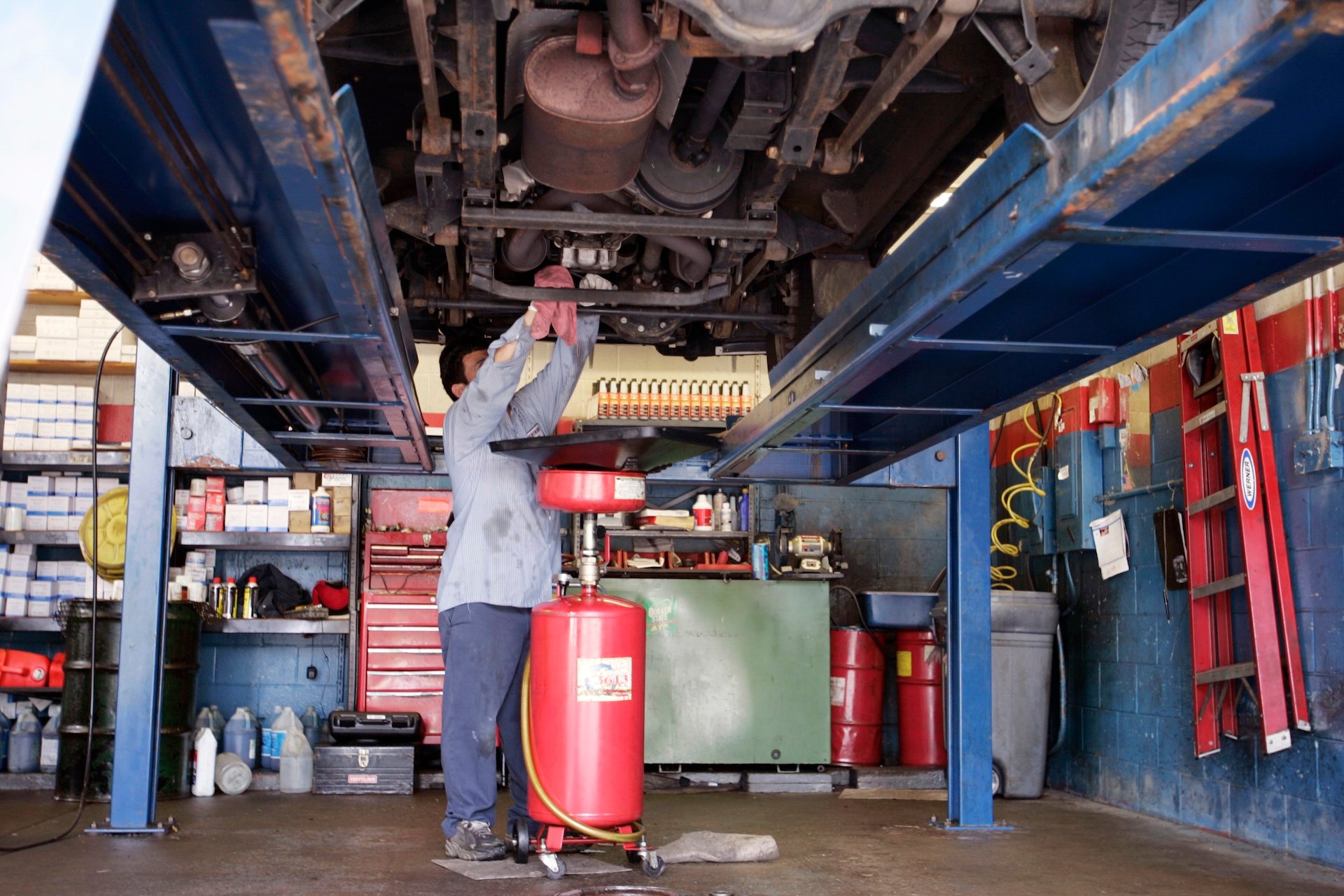 A mechanic at a 15 minute oil change store changes the oil in an suv. Automobile manufactures recommend owners change the oil in their car every 3,000 miles. (Photo by Najlah Feanny/Corbis via Getty Images)