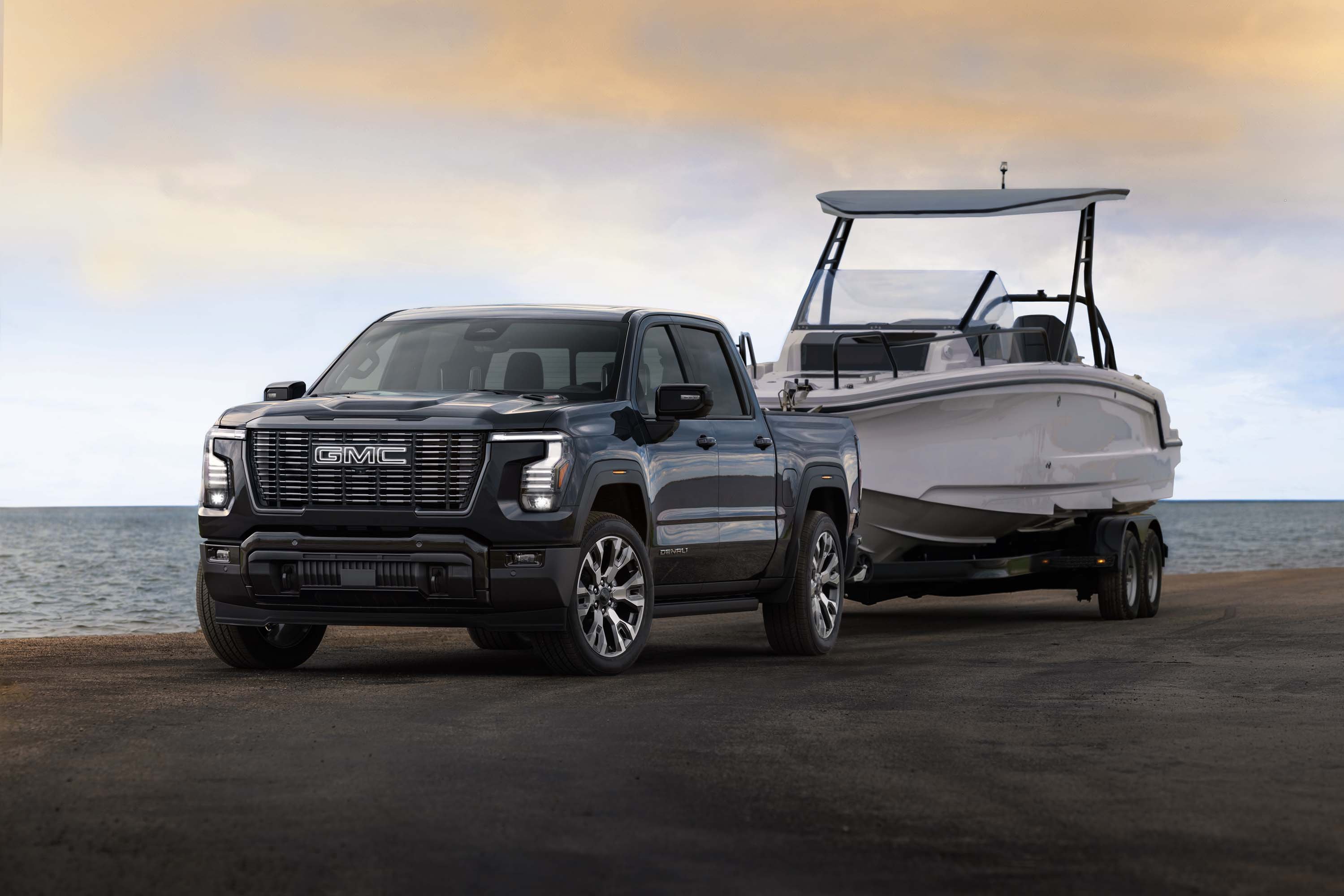 2027 GMC Sierra 1500 Denali Ultimate in Dark Ridge Metallic towing a boat. Exterior 3/4 shot. Preproduction model shown. Actual production model may vary.