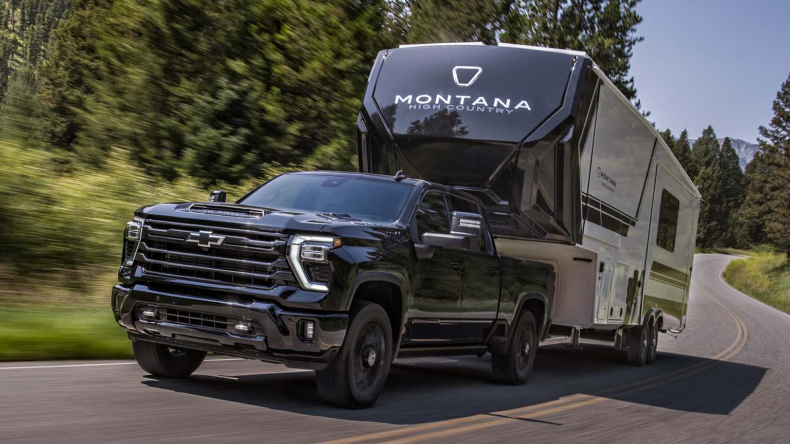 2027 Chevy Silverado HD pulling a fifth-wheel camper down the highway