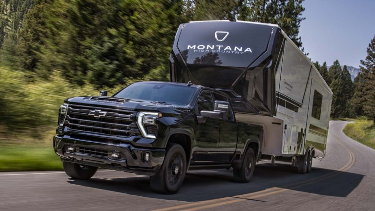 2027 Chevy Silverado HD pulling a fifth-wheel camper down the highway