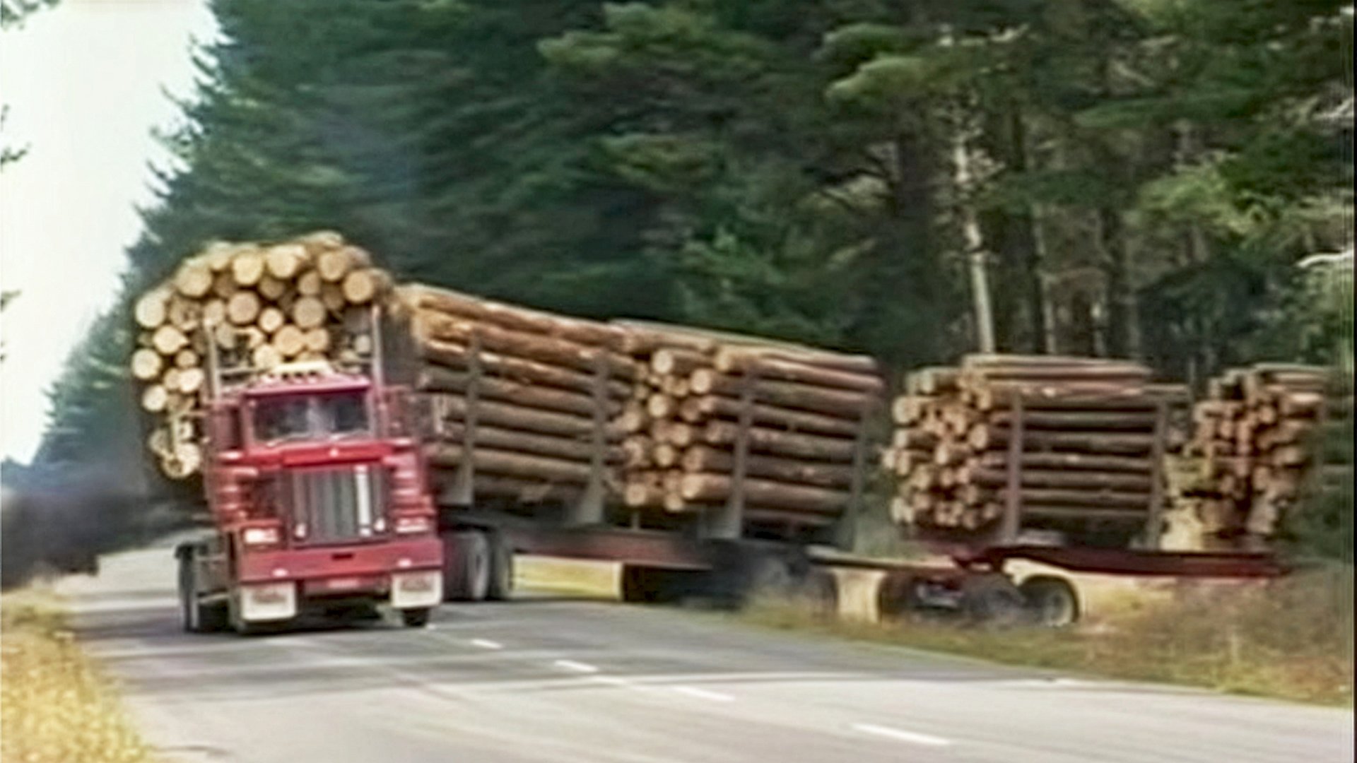 twin engine logging truck emerges from forest in New Zealand with a full load