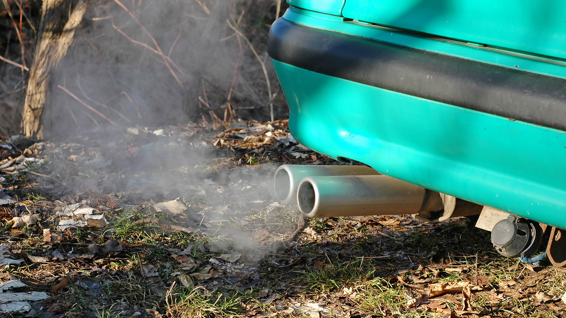 An exhaust tailpipe spews vapor on a cold day.