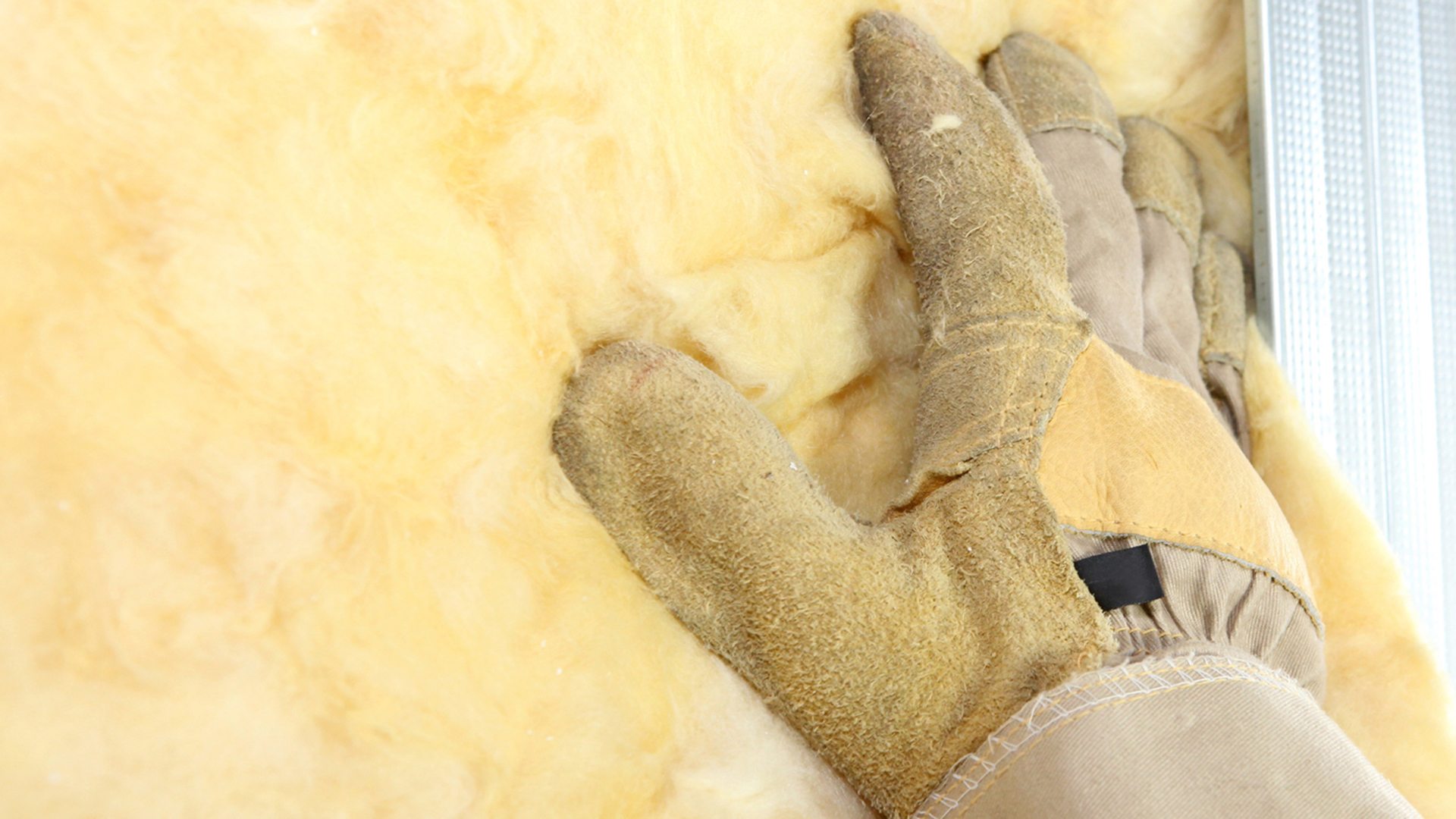 A sturdy work glove pats down insulation.