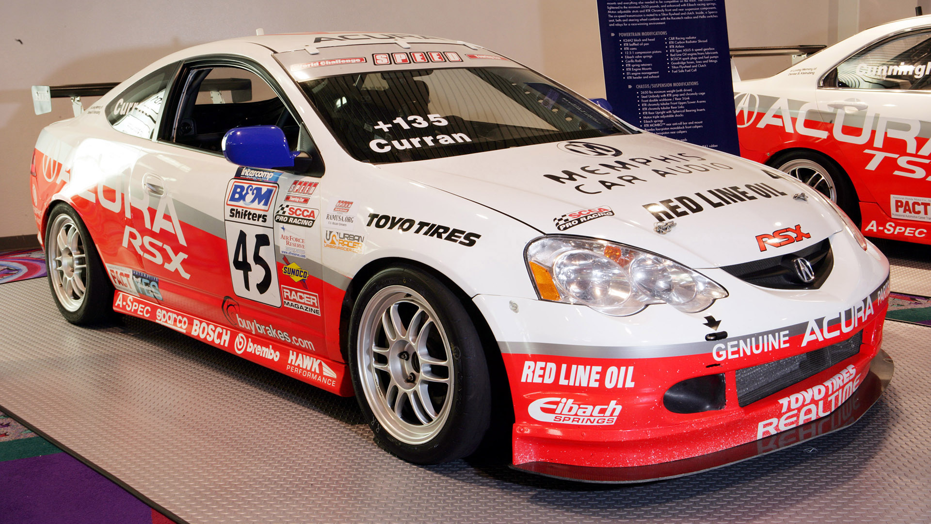An orange, silver, and white, Realtime Racing Acura RSX.