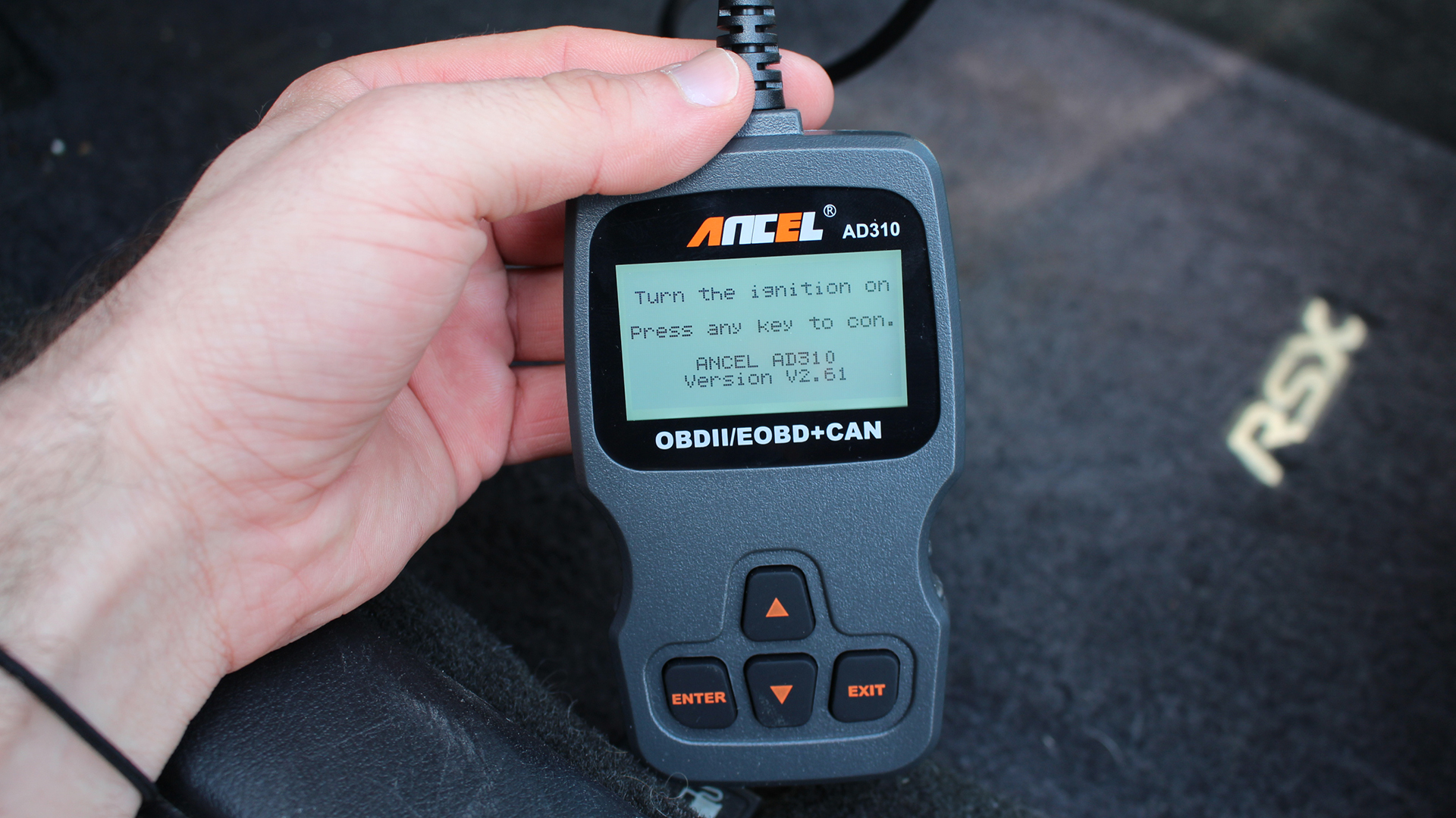 An Ancel OBD scanner in an Acura RSX footwell.