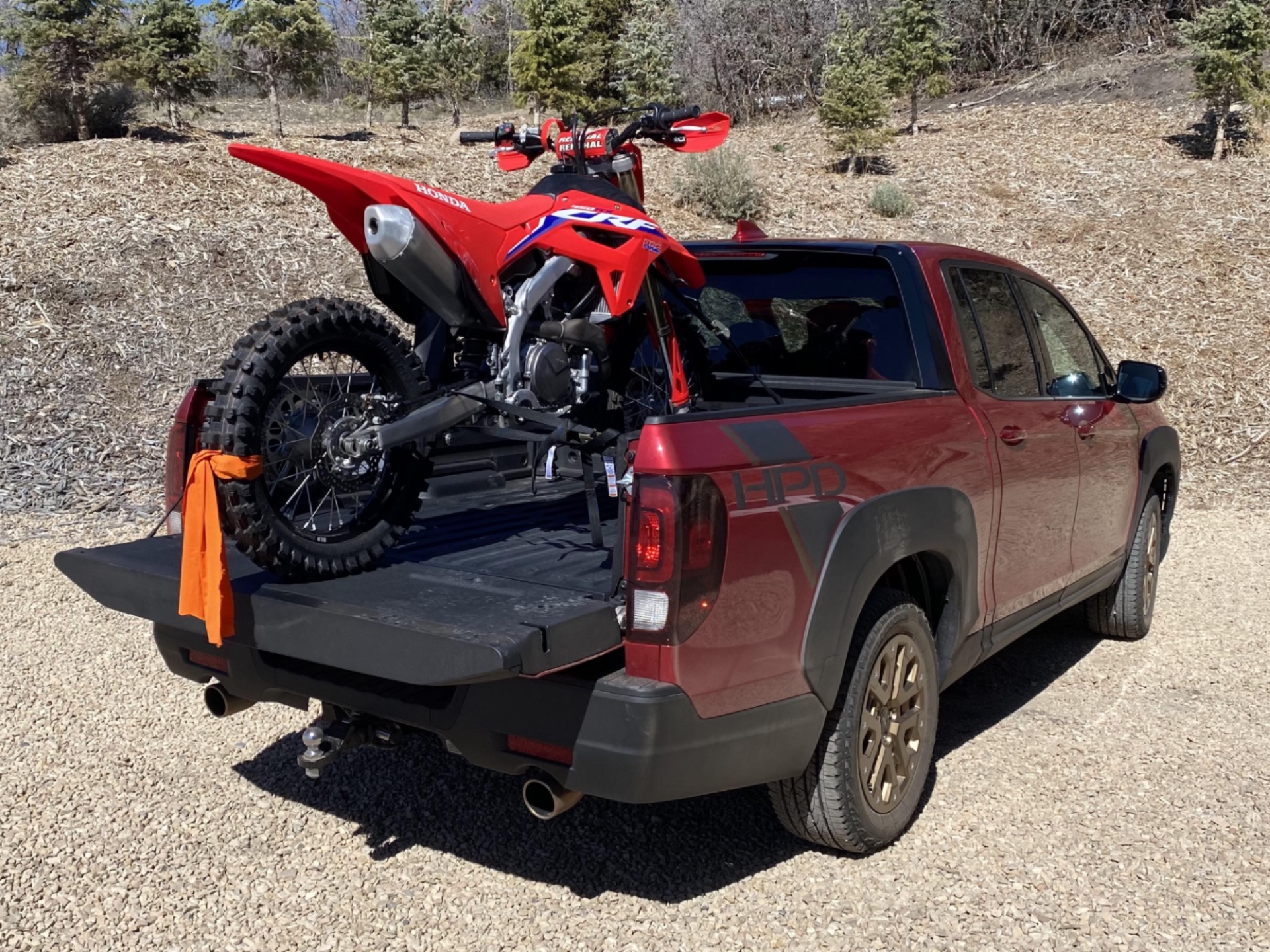 A red CRF450RX in the bed of a 2021 Honda Ridgeline.