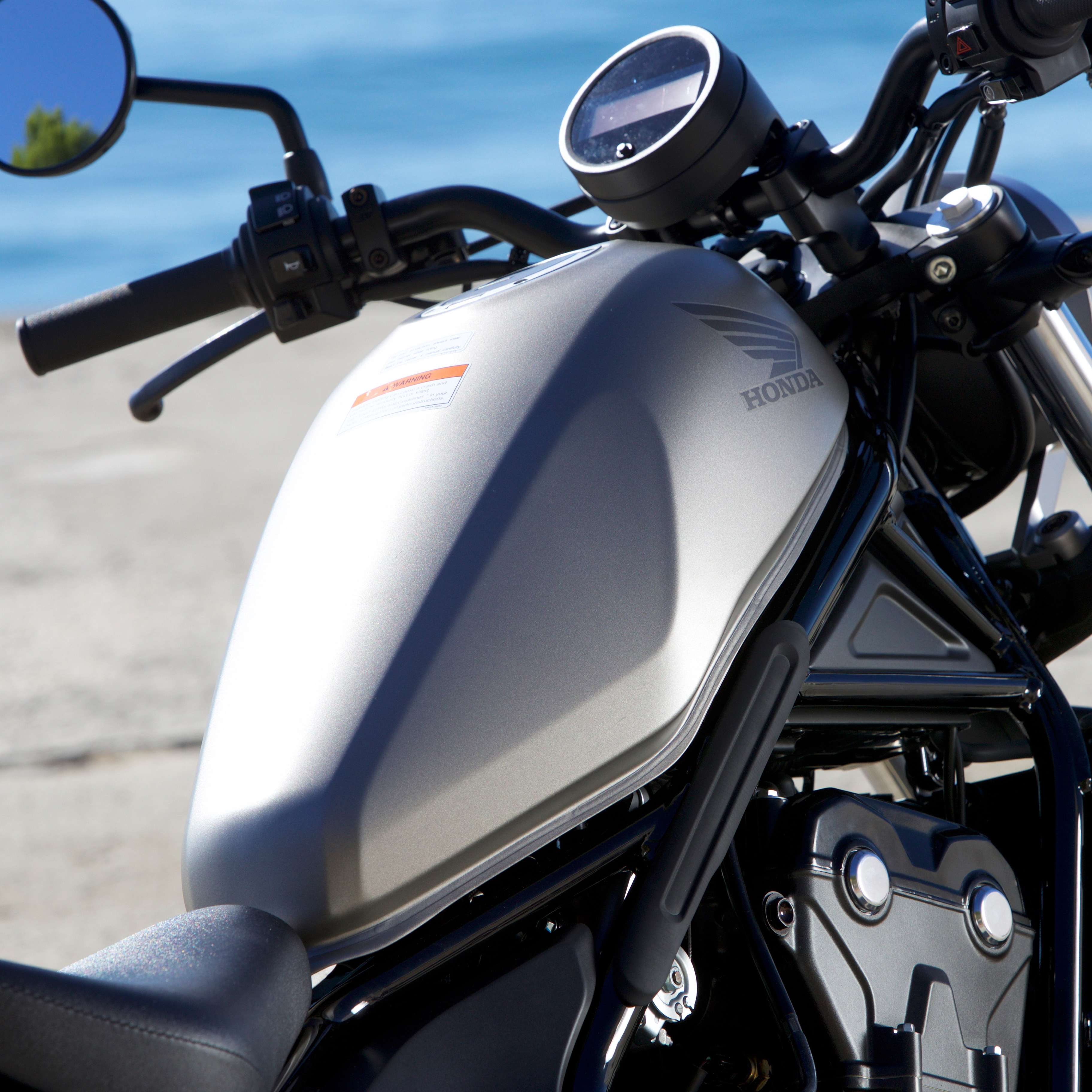 A light gray gas tank on a Honda motorcycle.